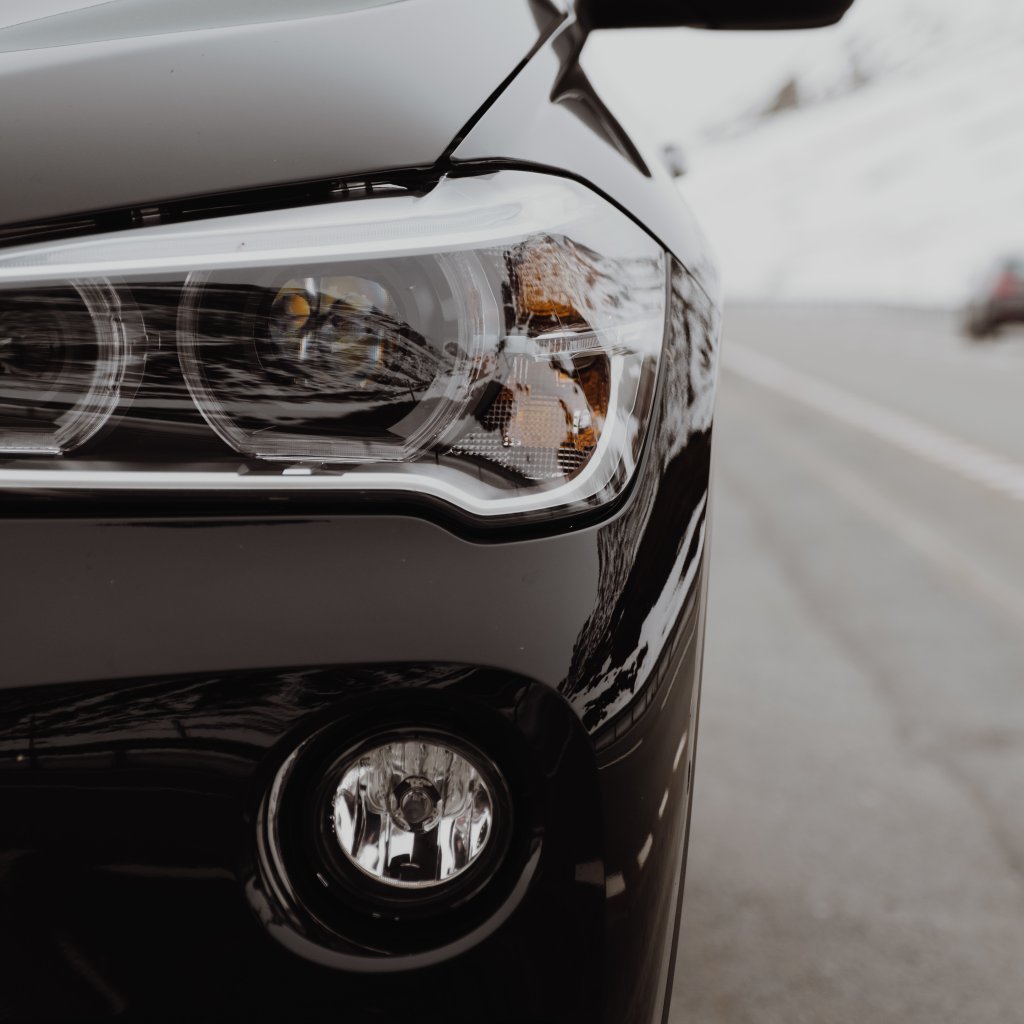 A vertical shot of the left part of a black expensive car on the road - perfect wallpaper, background